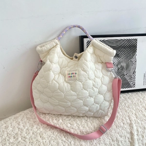 Detail van de witte gewatteerde tas met geborduurd label en geweven handvat