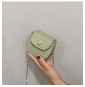 Détail du mini sac selle vert clair avec bandoulière chaîne dorée et bouton en cuir