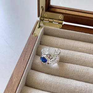 Detail of S925 silver ring with irregular lava texture and an oval blue gemstone