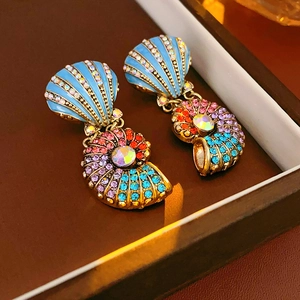 Detailed macro of vintage gold shell earrings with blue enamel and colorful rhinestones