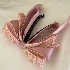 Close-up of pink satin and gold tweed bow hair clip with black banana clip base