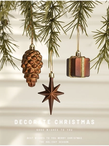 Close-up of bronze pine cone, star and gift box ornaments hanging on pine needles