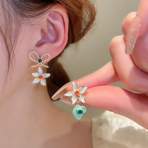 Elegant asymmetrical floral bow earrings with white enamel petals and gold plating