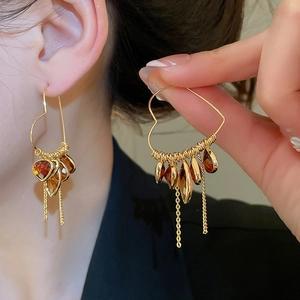 Detail of 18K gold-plated heart earrings with amber crystal drops and metal tassels