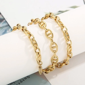 Macro shot of polished gold anchor link chain necklace on a minimalist display