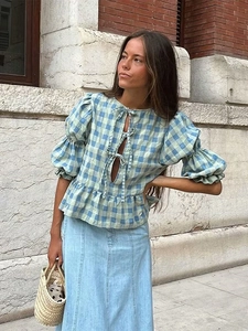 Detail of plaid blouse with ruffle hem and puff sleeves paired with denim skirt