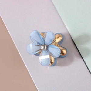 Close-up of blue resin flower hair clip with sparkling petals and gold metal grip