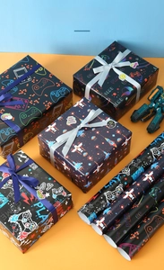 Detail view of cartoon game themed wrapping paper featuring gamepads and pixel rockets