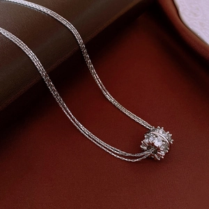 Macro-opname van een zilveren gelaagde ketting met een sprankelende zirkoon cilinder hanger