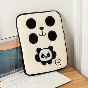 Dettaglio custodia per laptop con panda ricamato appoggiata a un MacBook su un tavolo