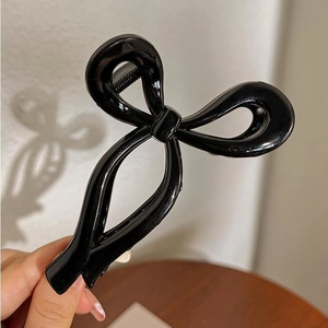 Glossy black jelly ribbon hair claw clip for high ponytail styling held in hand