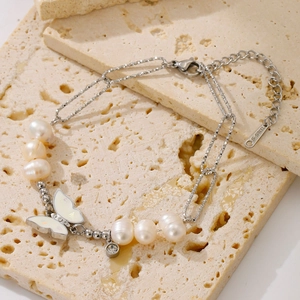 Detail of stainless steel bracelet with butterfly pendant and freshwater pearls