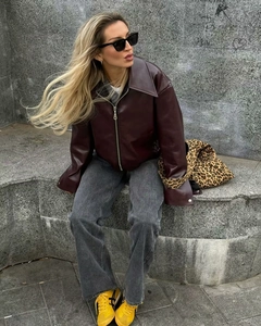 Giacca in pelle bordeaux con cerniera argentata mostrata in uno scatto fashion di strada