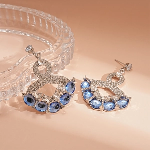 Detailed macro of vintage silver needle earrings featuring blue gemstones and pavé crystals