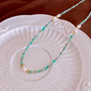 Collier en amazonite et perles dorées présenté sur une assiette en relief blanc