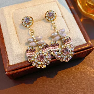 Vintage drop earrings with purple crystal and beaded floral accents on leather box