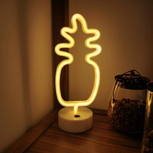 Warm yellow pineapple LED neon night light with base on wooden table for room decor