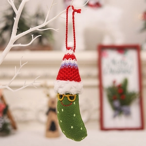 Funny green Christmas pickle ornament with red hat and glasses on a holiday tree branch