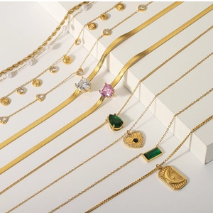 Detail view of gold layered necklaces with moon, shell, and zircon pendants on steps