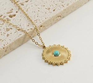 Macro detail of sunburst pendant necklace with turquoise stone on gold steel chain