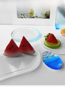 Artistic decorative resin coasters in fruit and ocean themes on a white tabletop