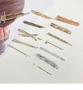 Flat lay of gold and silver alloy hair clips with pearls and resin wave designs