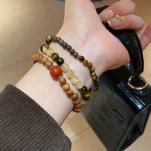 Close-up of layered beaded bracelet with tiger eye stones and gold accents on wrist