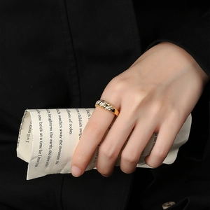 Gold plated twisted croissant ring with zircon inlay worn by model against dark background