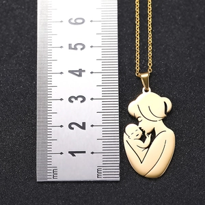 Golden mother and baby pendant showing size reference of 40mm height on a black ruler