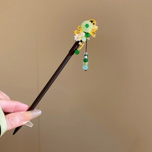 Close-up of wooden hair pin with gold metal flowers and green beaded tassels
