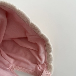 Close-up of soft pink cotton lining and beige knit edge on a warm baby winter hat