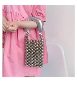 Dettaglio borsa a mano argentata per bambina con manico spesso e texture di perle metalliche
