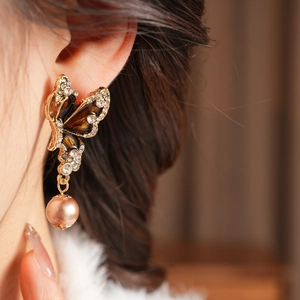 Detailed close-up of a vintage butterfly earring with sparkling rhinestones and a pearl drop