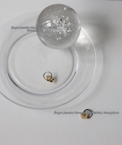 Detail of silver hoop earrings with gold daisy charms on clear glass decor