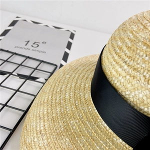 Close-up of fine woven straw texture and black ribbon detail on a French sun hat