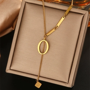 Detailweergave van de gouden stalen Y-ketting met O-hanger en zijden achtergronddecoratie