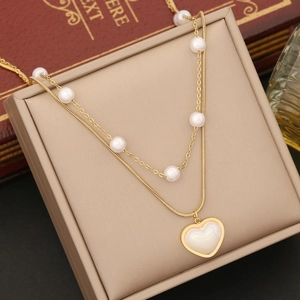 Double-layered gold necklace with pearls and heart shell pendant on jewelry box