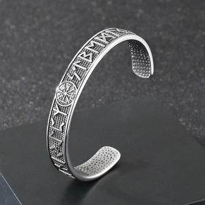 Detailed view of stainless steel Viking compass and Nordic runes on a silver cuff bracelet