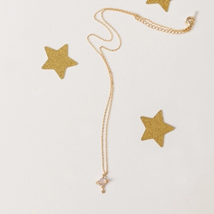 Detailed close-up of a golden planet pendant necklace with a pink gemstone and star charm