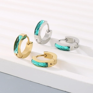 Detailed view of gold and silver hoop earrings featuring emerald green square zircons