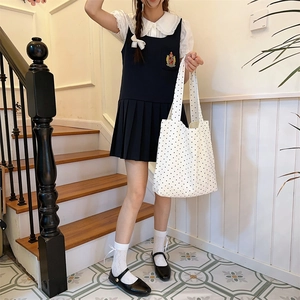Close-up of a student carrying a white canvas tote bag with black polka dot pattern