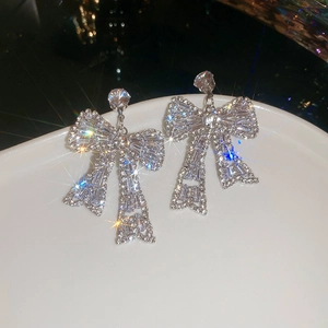 Macro shot of silver bow stud earrings with shimmering rhinestones and starburst glow