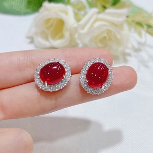 Close-up of pigeon blood red oval ruby earrings surrounded by white zircon accents