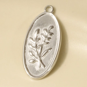 Detailed macro view of an oval stainless steel pendant with embossed leaf patterns