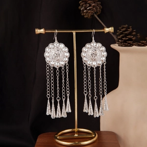 Close-up of Bohemian silver tassel earrings with geometric discs on a display stand