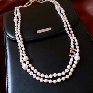 Detail of a double-layered pearl necklace with golden beads and a sparkling crystal charm