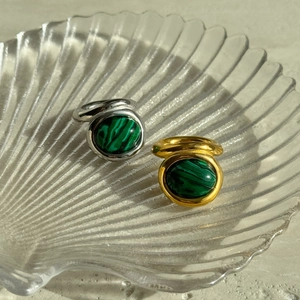 Close-up of 18k gold and silver plated titanium rings with oval malachite stones