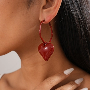 Close-up of red oil-drop heart pendant hoop earrings with a glossy vintage finish