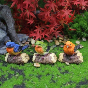 Three colorful resin bird figurines with feather details on wooden bases for garden decor