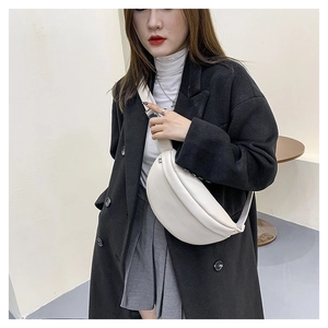 White crescent crossbody bag styled on a black wool coat for a chic contrast